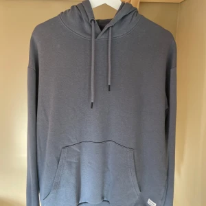 Grå hoodie från Jack & Jones - Säljer en skön hoodie som inte längre kommer till användning. Passar både tjej å kille. Skick 7/10