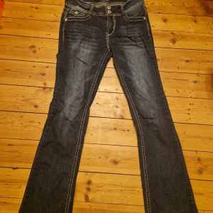 Mörkblå jeans med broderade bakfickor - Snygga mörkblå jeans med rhinestones på bakfickorna. De är low waist och bootcut/flare. Från märket wallflower men är miss me liknande! Enbart använda ett fåtal gånger. 28w 30l skulle jag tro