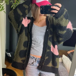 Camouflage kofta med rosa detaljer - Säljer en jättesnygg unik kofta med camouflage-mönster i grönt och svart och rosa. Koftan har knappar framtill och långa ärmar. Lite nopprig men kan tas bort med nopprrmaskin🩷🩷