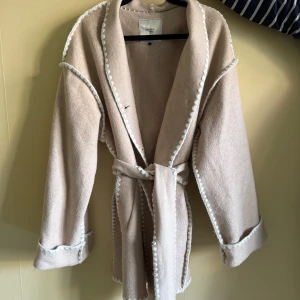 Vår kappa - Säljer min nästan helt oanvända vårjacka som inköptes förra året. Den är beige/vit i ullmaterial men ändå tunn nog för våren. Säljer då jag inte fått användning för den. Det är en storlek 36 men jag skulle säga att den passar en 38 också. 