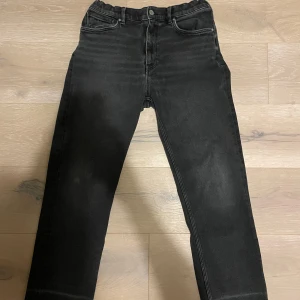 Svarta jeansbyxor från GANT - Snygga svarta jeansbyxor från GANT med en klassisk design. Byxorna har en midwaist passform och är tillverkade i ett slitstarkt material, Nypris 700kr. Otroligt fina för en klassisk look. 