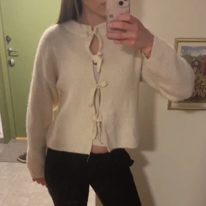 Vit kofta med knytband - Superfin vit kofta med knytband framtill. Tröjan är stickad och har långärmade ärmar med en lite boxig och avslappnad passform.