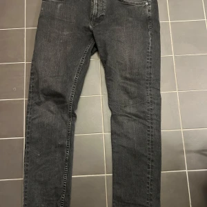 Svarta jeans från Nudie Jeans - Snygga svarta jeans från Nudie Jeans med klassisk femficksdesign. De har en normal passform och är tillverkade i slitstarkt denim. Perfekta för en stilren look.