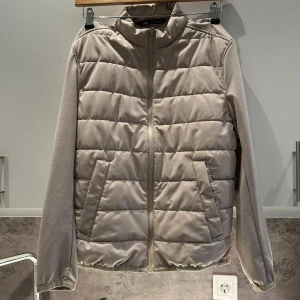 Beige quiltad jacka från Zara - Säljer en stilren beige  jacka från Zara. Perfekt för kyligare dagar med sin pufferdesign som ger extra värme. Enkelt att matcha med olika outfits 🤩Pris går självklart att diskutera🤩