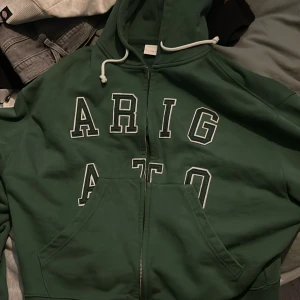 Grön hoodie från Axel Arigato - Säljer en snygg grön hoodie från Axel Arigato med dragkedja. Perfekt för en avslappnad stil. Säljer pågrund av den är för liten, bra skick