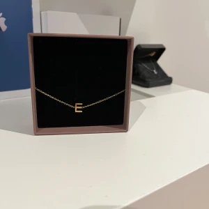Guldarmband med bokstav E - Elegant guldarmband med en enkel kedja och en bokstavsberlock i form av ett E. Perfekt för att ge en personlig touch till din stil. Kommer i asken från Edblad. Säljer då jag köpte det när jag var tillsammans med min kille men vi gjorde slut. Inga defekter. Köpte för 300kr.