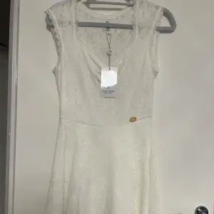 Elegant vit spetsklänning från Chi Chi London med vacker spetsdetaljering. Klänningen har en ärmlös design och en klassisk rund halsringning. Perfekt för sommarens festligheter eller en romantisk middag. 💫