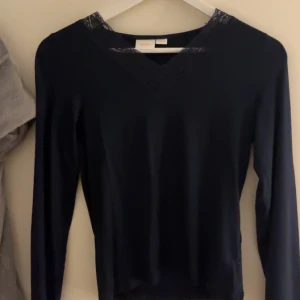 Mörkblå långärmad topp med spetsdetaljer - Elegant mörkblå  långärmad topp med v-ringad hals och spetsdetaljer vid halsringningen. Perfekt för en stilren look storlek 158/164 passar en XS .