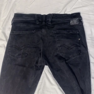 Svarta jeans från Replay - Snygga svarta jeans från Replay med klassisk femficksdesign och knappgylf. Perfekta för en stilren look. Märkesdetaljer på bakfickan och bältesslingor för extra stil. Kontakta vid frågor.