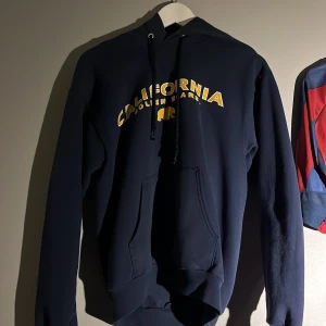 Mörkblå hoodie från Hanes - Säljer en mörkblå hoodie från Hanes med texten 'California Golden Bears' i gult på bröstet. Tröjan har en klassisk känguruficka och justerbar huva med dragsko. Perfekt för en avslappnad stil. Säljer denna supersköna hoodie pga använder inte längre. Storlek S men passar XS😊