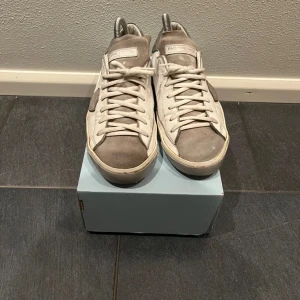 Vita sneakers från Philippe Model - Snygga vita sneakers från Philippe Model med grå detaljer. Skorna har klassisk snörning och en stilren design. Perfekta för en avslappnad look.