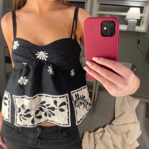 Svart och vit blommig linnetopp från Zara - Snygg svart och vit linnetopp från Zara med blommigt mönster. Toppen har smala axelband och en luftig passform. Perfekt för varma dagar och kan enkelt matchas med jeans eller kjol.