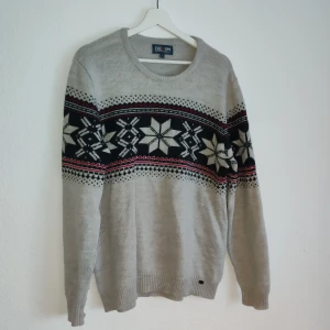 Grå tröja från Denim by Hampton Republic 27 - Säljer en snygg grå tröja från Denim by Hampton Republic 27 med ett stilrent mönster i svart och vitt samt röda detaljer. Tröjan har långa ärmar och är perfekt för kyligare dagar. Passar bra till både jeans och chinos.