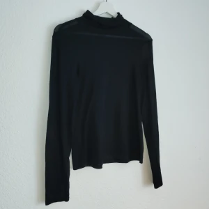 Svart långärmad polotröja från Gina Tricot - Snygg svart långärmad polotröja från Gina Tricot. Perfekt för kyligare dagar med sin stilrena design och bekväma passform. Ett måste i garderoben för en klassisk look.