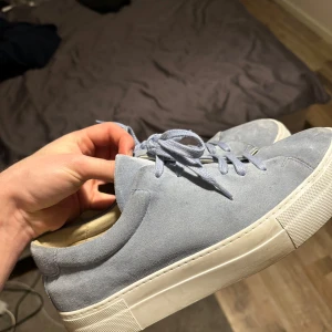 Blå sneakers från Paul & Friends - Snygga blå sneakers från Paul & Friends med vit sula och snörning. Perfekta för en avslappnad stil. Tillverkade i mocka för en stilren look. Nypris ligger på 2200kr och finns ej att få tag på i denna färg längre.