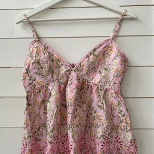 Blommig topp från BikBok - Söt rosa topp från BikBok med blommigt mönster. Den har smala axelband och v-ringad. Aldrig använd.