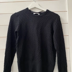 Svart stickad tröja från Kappahl - Säljer en stilren svart stickad tröja från Kappahl. Tröjan har ett diskret mönster och långa ärmar, perfekt för kyligare dagar. Den är i storlek S och passar bra till både jeans och kjol. Ett måste i garderoben för en klassisk look.