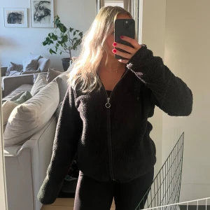 Svart tunn teddyjacka med dragkedja - Mysig svart teddyjacka med dragkedja framtill.  Jackan har långa ärmar och en avslappnad passform.