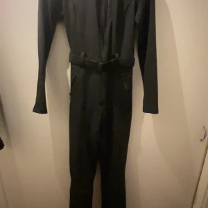 Svart skidoverall från Zara - Snygg svart skidoverall från Zara Ski Collection. Den har en tight passform med ett bälte i midjan och dragkedja längs benet. Perfekt för skidåkningen. Har använts 1 gång förra året men har nu tyvärr blivit för liten den har inga täcken på användning alls!