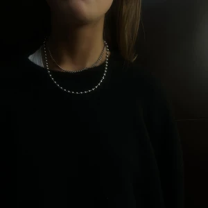 005 - Elegant silverfärgat halsband med en enkel och stilren design. Perfekt för att lägga till en touch av elegans till vilken outfit som helst.