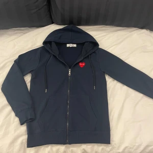 Cdg zip-hoodie  - Säljer denna full-zip hoodien från Cdg. | Skicka är så gott som nytt. | Den är i en mörkblå/marinblå färg men en röd logga. | Det är bara att höra av sig om man har några frågor eller funderingar kring hoodien⭐️⭐️⭐️