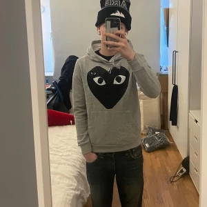 Cdg-Hoodie - Hoodie från Comme des Garçons i storlek S. | Den är i utmärkt skick. | Den har en mindre broderad logga på vänster sida bröstet och ett större tryckt hjärta över framsidan av hela bröstet. | Stygnen vid kanten vid ena fickan har gått upp. Men det är lätt att sy tillbaka. |Det är bara att höra av sig om man har några frågor eller funderingar⭐️⭐️⭐️