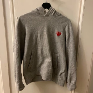 Grå hoodie från Comme des Garçons - Hej, jag säljer en stilren grå hoodie från Comme des Garçons med det ikoniska röda hjärtat på bröstet. Hoodien är väldigt bekväm och i toppskick. Pris kan diskuteras, buda gärna. Mvh Emil. 