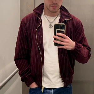 Vinröd jacka - Säljer en snygg vinröd jacka från Han Kjøbenhavn med tunna ränder. Jackan är i väldigt bra skick men finns ett hål på insidan av jackan som går att fixa. Därav priset. Jag är 175 