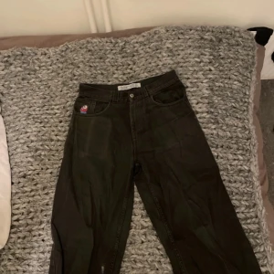 Svarta big boys med gubben i fickan  - Snygga svarta jeansbyxor med en cool broderad detalj på fickan. Byxorna har en klassisk femficksdesign och en bekväm passform. Perfekta för en avslappnad stil. Det står xs men passar mig som burkar ha större. Den har ett litet hål i bakfickan men det går ganska lätt o sy ihop troligtvis. Den lilla fläcken på benet e borta men orkar inte ta en ny bild.