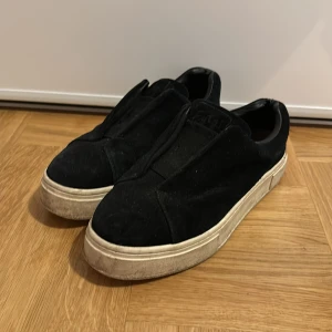 Eytys skor - Snygga svarta sneakers i mocka med en stilren design. Skorna har en tjock vit sula och saknar snörning för en smidig på- och avtagning. Perfekta för en avslappnad stil.
