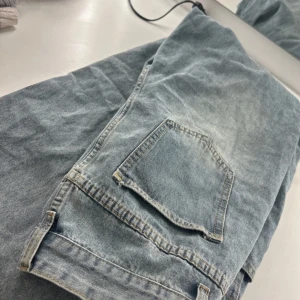 Blå jeans med fickdetalj - Snygga blå jeans med en cool fickdetalj på sidan. Perfekta för en avslappnad stil. De har en ljus tvätt som ger en vintagekänsla.