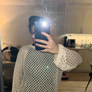 Beige stickad tröja - Säljer en beige stickad tröja med ett öppet nätmönster. Tröjan har långa ärmar och en avslappnad passform, perfekt för lager-på-lager-stil. Den är både trendig och bekväm, idealisk för kyligare dagar.