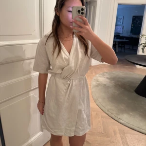 Beige omlottklänning från & other stories  - Säljer en stilren beige omlottklänning från & other stories. Klänningen har korta ärmar och en klassisk krage. Oanvänd med lapp kvar. 