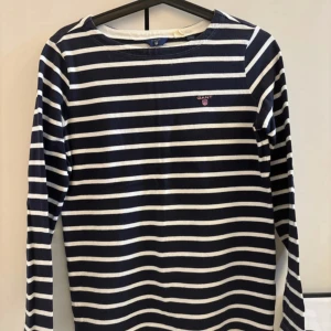 Randig långärmad tröja från Gant - Säljer en snygg randig tröja från Gant i marinblått och vitt. Tröjan har långa ärmar. Den är gjord i bomull och har en klassisk passform. Perfekt för både vardag! Det står storlek (158-164)