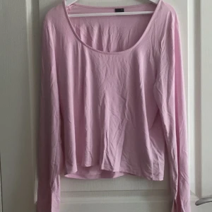 Rosa långärmad topp från Gina Tricot - Säljer en söt rosa långärmad topp från Gina Tricot. Den har en rund halsringning och är tillverkad i ett mjukt material som känns skönt mot huden. Perfekt för en avslappnad stil.