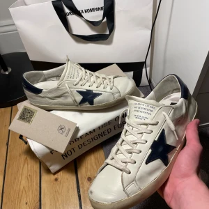 Golden goose superstar 45 - Säljer dessa golden goose i bra skick, storlek 45 Köpta på NK för 5600 kr i april. ALLT OG MEDFÖLJER 💯Heeldrag lite sliten. Kom PM för mer bilder 