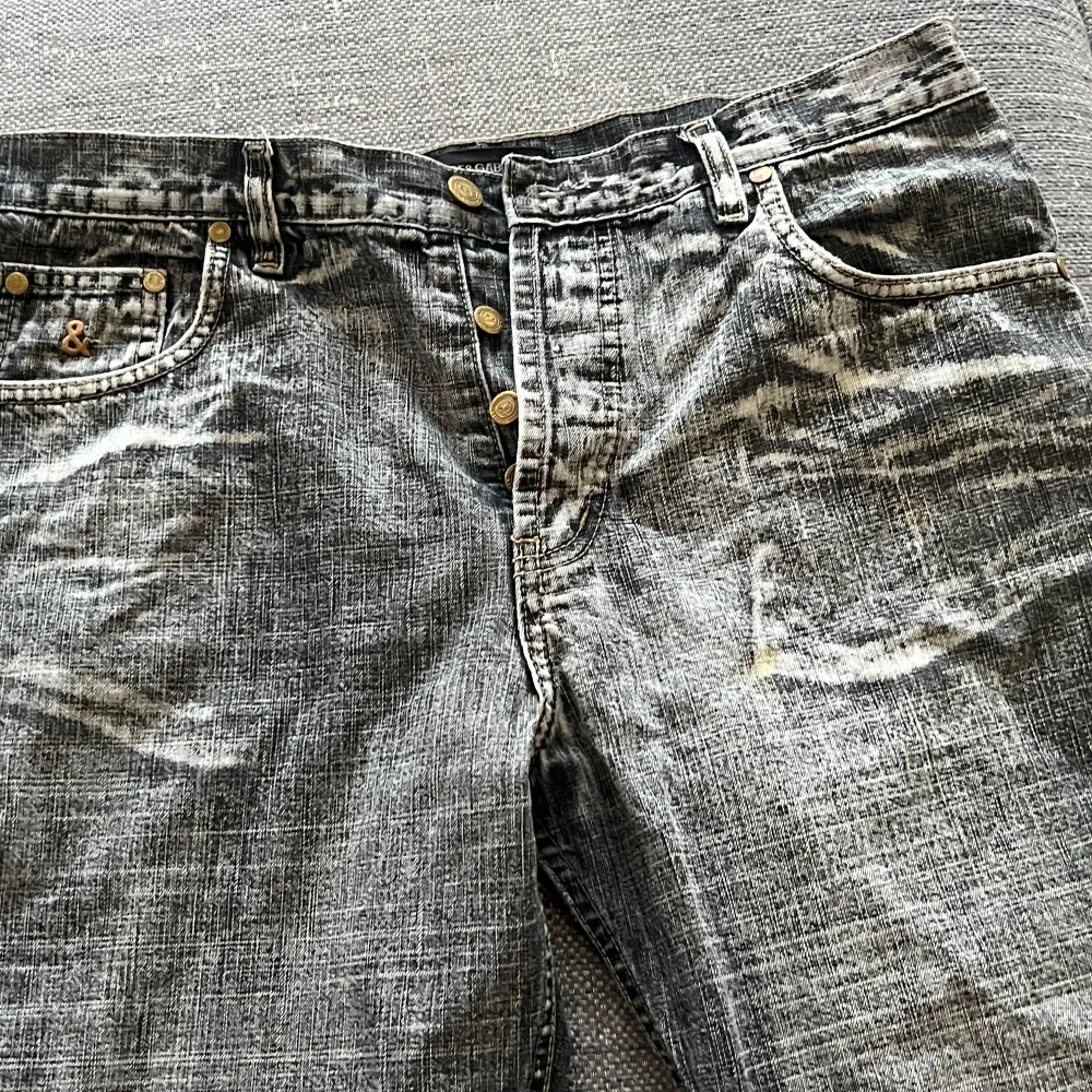 Säljer ett par grå jeans från Dolce & Gabbana. De har en cool, sliten look med ljusa tvättade detaljer. Jeansen har knappar framtill och klassiska fem fickor. Perfekta för en avslappnad stil!. Jeans & Byxor.