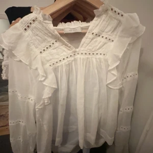 Vit blus med volangdetaljer - Säljer en superfin vit blus med volangdetaljer och spets. Den har en v-ringad design och långa ärmar. Perfekt för både vardag och fest! 🤍