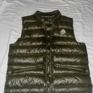 Moncler väst - Säljer en moncler gui väst i väldigt fin olivgrön färg, använd ett fåtal gånger så är i väldigt fint skick