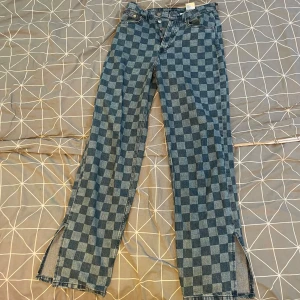 Rutiga jeans med slits - Säljer ett par rutiga jeans med slitsar längst ner. Använda ett fåtal gånger. 