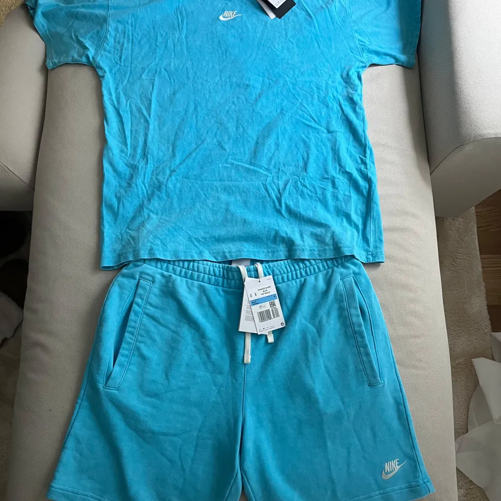 Snyggt set från Nike i en härlig blå färg. T-shirten har en liten logga på bröstet och shortsen har en större logga på benet.  Helt nytt med lapparna kvar.   Köpt som present till sambon men passade dessvärre inte honom.. T-shirts.