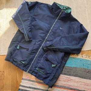 Nike ACG blå jacka 90’s - Riktigt fet höst/vår-jacka från Nike ACG. 90-tal någon gång troligtvis. Känns som ytan är lite regnavstötande. Dragsko i midjan. Storlek XL men passar också L.