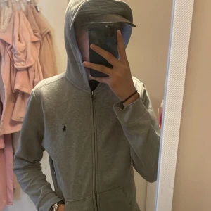 Grå polo hoodie  - Säljer en polo tröja i fint skick, inga fläckar eller dofter Storlek 160 Kan Hämtas i Uddevalla eller Göteborg  Annars är det fri frakt👌☺️