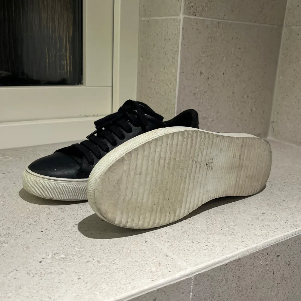 Säljer ett par svarta sneakers i skinn med snygga guldfärgade fågelbroderier på sidorna. Skorna har en vit sula och svarta snören. De är i bra skick och perfekta för både vardag och fest. Storlek 36 men passar mig som har 37. Skor.