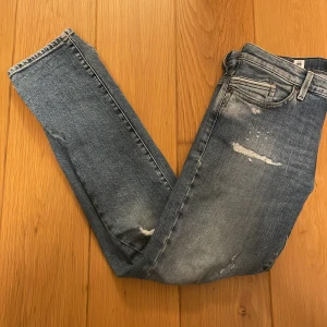 Blå jeans med slitningar - Snygga ljusblå/blåa jeans med slitningar för en trendig look. De har en klassisk femficksdesign och en slimfit/slimfit straight passform