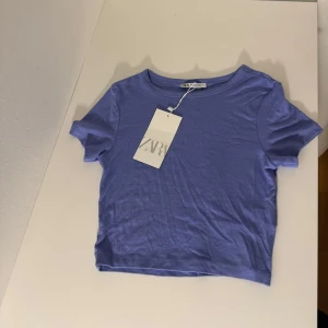 Lila kortärmad topp från Zara - Säljer en snygg lila kortärmad topp från Zara. Aldrig använd. Jätte skönt material och fin färg.