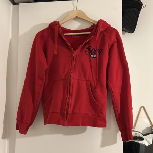 Röd hoodie från Svea  - Säljer en snygg röd hoodie från Svea. Säljer på grund av att den inte används längre. Använd fåtal gånger. Hoodien är i nyskick i storleken medium. Men upplever att den är liten i storleken och passar mera S.💗