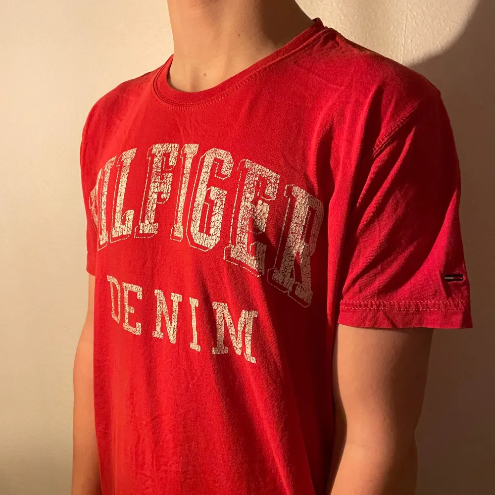 Snygg röd t-shirt från Tommy Hilfiger med tryck på bröstet. Perfekt för en avslappnad stil. Tillverkad i mjukt material för extra komfort. Inga defekter, använd ett par gånger . T-paidat.