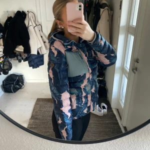 Mönstrad pufferjacka från Burton - Jacka från Burton med ett mönster i blått och rosa. Perfekt som vinterjacka eller skidjacka. Inte alls sliten och är i väldigt bra skick.