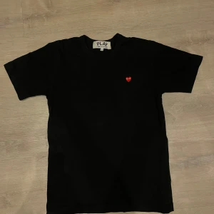 Svart t-shirt från Comme des Garçons  - Svart T-shirt i storlek S från Comme des Garçons. Nypris på denna ligger runt 1000 kr. Riktigt bra kvalitet och den enda anledningen att jag säljer är att jag växt ur den. Inte särskilt använd och i superbra skick. Hör gärna av er vid frågor!